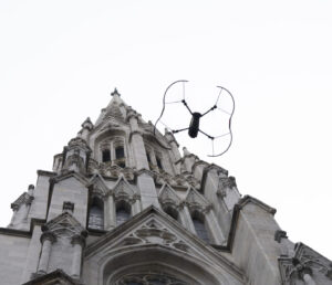 A drone performing a building inspection, flying around a tall building and taking high-res images