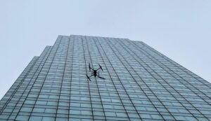 A drone flying around the exterior of a skyscraper to perform a facade inspection